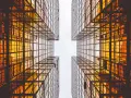 Looking up between four golden glass buildings, the architecture forms a cross shape, resembling a modern church.