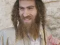 A smiling man with long, curly hair and a beard, wearing traditional Jewish attire. His appearance sparks curiosity about what ethnicity was Jesus.