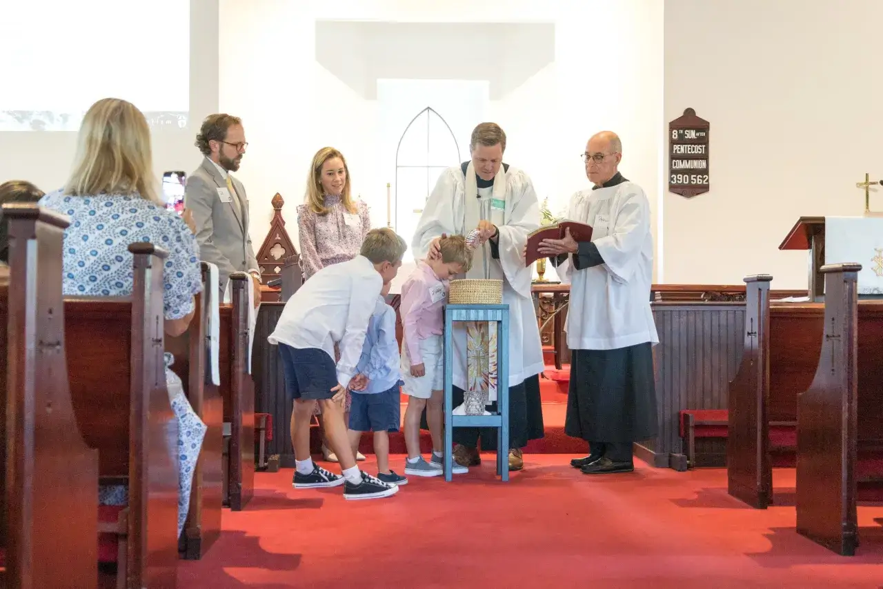 A baptism ceremony in progress, with a priest pouring water on a child's head, symbolizing sharing the gospel.